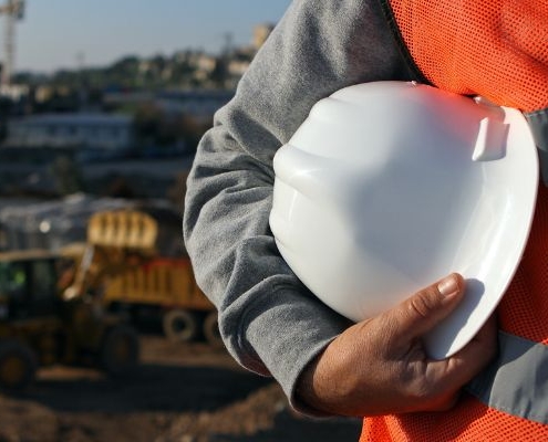 a Health & Safety Competent Person stands in front of the frame holding a hard hat