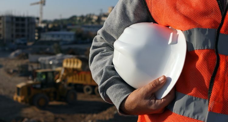 a Health & Safety Competent Person stands in front of the frame holding a hard hat